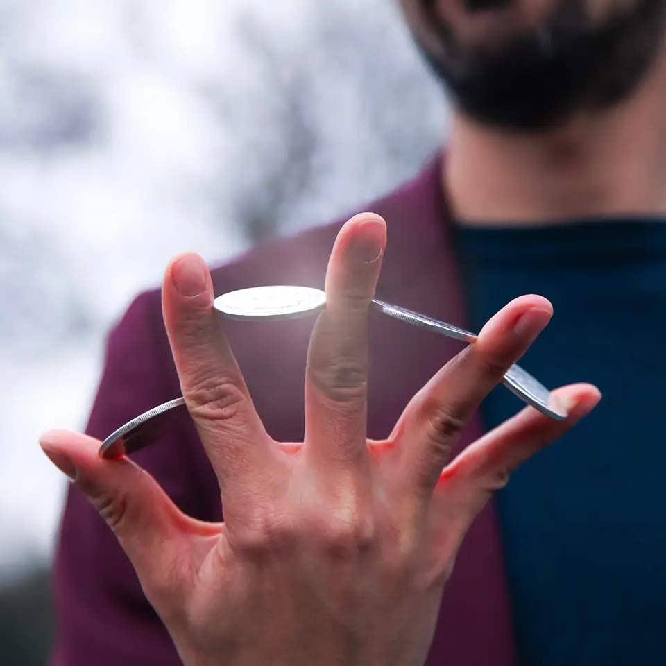 Magician holding a coin between each finger of their hand