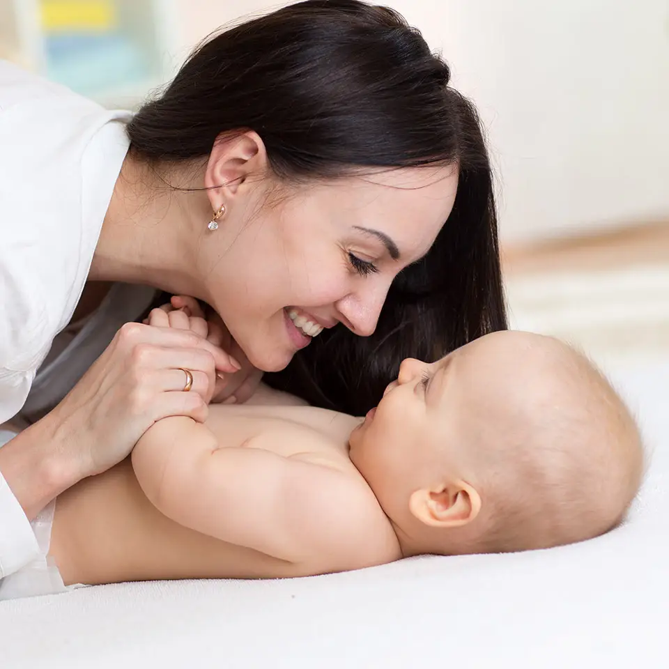 Mother holding baby, who is lying down